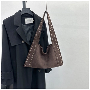 Detail of wide shoulder strap with golden metal studs on dark brown suede hobo bag