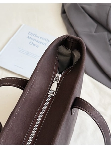 Gros plan d'un sac cabas marron foncé avec fermeture éclair argentée et coutures blanches