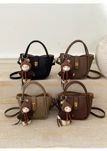 Détail de quatre sacs seaux colorés en cuir avec des breloques ours et des fermoirs