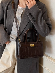 Deep brown croc-embossed crossbody bag with gold twist lock and round top handles