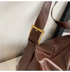 Close-up of dark brown leather tote strap with adjustable vintage gold buckle detail