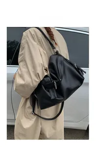 Close-up of black pebble grain leather tote bag with silver hardware on a model