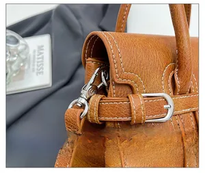 Detailed macro view of orange leather texture with silver metal buckle and white stitching