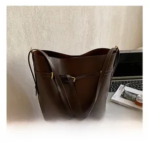 Close-up of a large coffee brown bucket bag with gold pin buckle and sleek strap