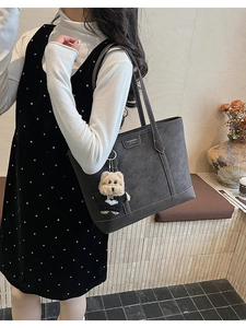 Détail d'un cabas gris foncé en cuir grainé avec coutures contrastées et porte-clé chien