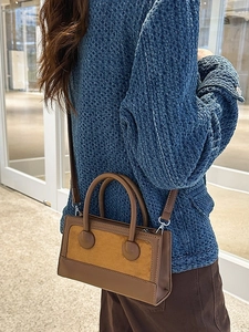 Retro brown and yellow leather handbag with crossbody strap worn by a model