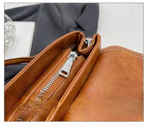 Detailed macro view of silver smooth metal zipper and textured brown leather on handbag