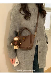 Detail of brown vintage suede tote with gold clasp, bear charm and shoulder strap