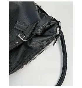 Close-up of black lychee grain leather stitching and silver metal buckle detail
