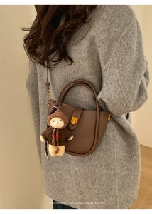 Détail d'un sac cabas en cuir marron avec fermoir doré et pendentif d'ours en peluche mignon