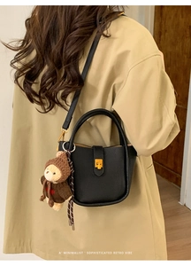 Détail du sac seau en cuir noir avec serrure dorée et breloque ours mignon