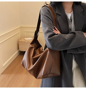 Side view of a brown vintage tote bag worn by a model in a minimalist indoor setting