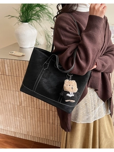 Détail du sac cabas noir avec surpiqûres blanches et pendentif en forme d'ours en peluche