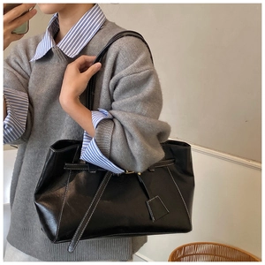 Détail d'un sac cabas en cuir noir avec surpiqûres blanches contrastées et fines bandoulières