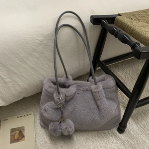 Détail du sac fourre-tout gris en fausse fourrure avec breloque et bandoulières en cuir