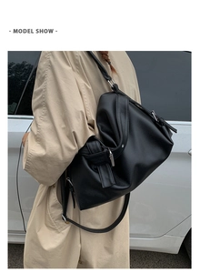 Close-up of black lychee grain faux leather tote bag with decorative side buckles