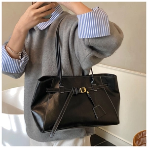 Vue latérale du grand sac cabas noir brillant avec surpiqûres blanches et boucle en métal
