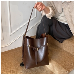 Detail of dark brown vintage leather bucket bag featuring a decorative belt buckle and strap