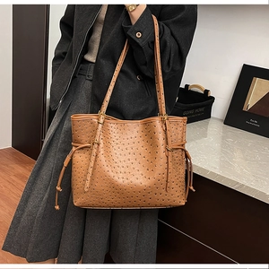 Deep brown ostrich pattern leather tote bag with adjustable strap shown on shoulder