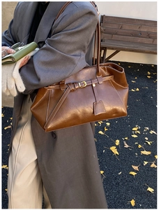 Sac cabas en cuir marron assorti à un manteau en laine grise sur un banc en automne