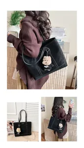 Détail du sac cabas noir avec coutures contrastées et charmant pendentif d'ours en peluche