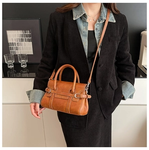 Detail of tan leather doctor bag featuring fine stitching and metal buckle accents