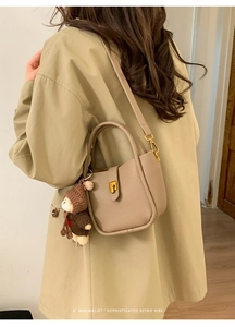 Détail du sac seau en cuir grainé kaki avec charme d'ours et fermoir en métal doré
