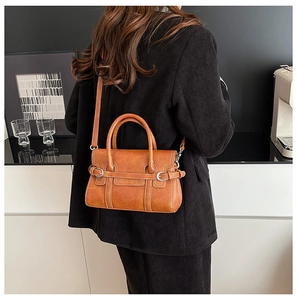 Close-up of brown vintage leather handbag with decorative metal buckles and dual strap style