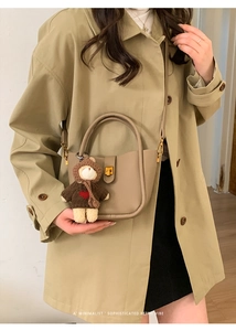 Détail du sac seau en cuir kaki avec breloque ours et fermoir en métal doré