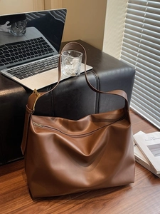 Vintage brown leather tote bag with laptop and books in a modern office setup
