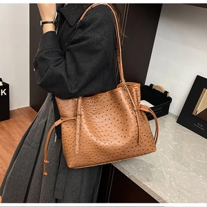 Detail of ostrich embossed brown tote bag featuring side drawstring design and long strap