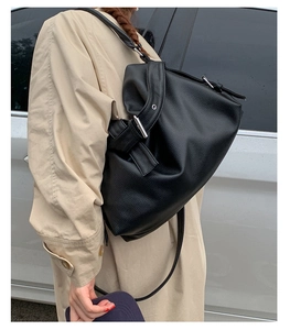 Outdoor shot of a black pebbled leather hobo bag with adjustable silver buckle strap