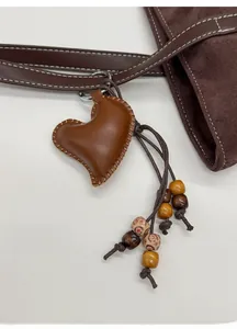 Detailed close-up of a brown leather heart-shaped handmade charm with wooden beads