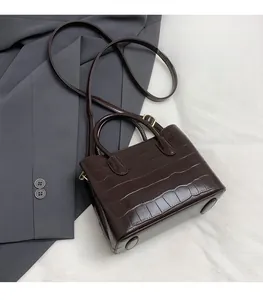 Détail de la texture croco marron foncé sur un sac seau élégant en similicuir