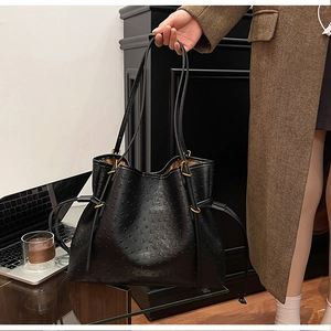 Close-up of black ostrich texture tote bag with drawstring detail and gold hardware