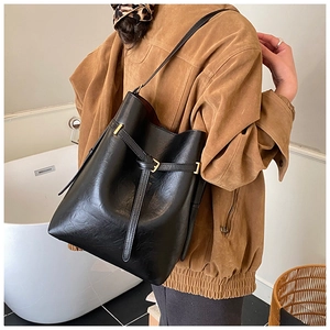 Black leather bucket bag detail with slim buckle strap and polished metal buckle