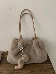 Sac seau en fausse fourrure beige avec breloque botte mignonne sur table en bois