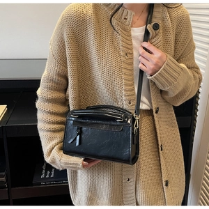 Détail de la texture en cuir souple noir avec effet craquelé vintage et fermeture à pompon
