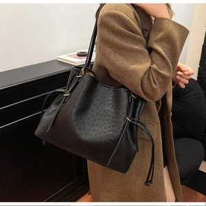 Detail of black ostrich embossed leather underarm bag with drawstring and gold hardware