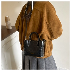 Détail du sac à main noir motif crocodile pour femme avec finitions dorées chic