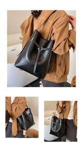 Detail view of black oil wax leather bucket bag with gold hardware and drawstring detail