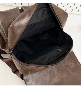 Close-up of brown PU backpack interior with black fabric lining and zipper compartment