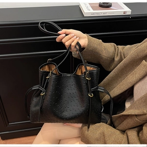Detail of black ostrich embossed hobo bag with drawstring closure and golden hardware