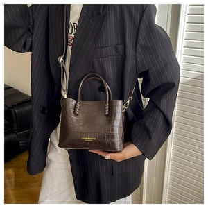 Détail du cabas en cuir crocodile marron foncé élégant avec logo doré de la marque