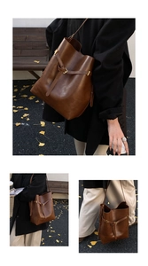 Detail of a brown leather bucket bag showing adjustable buckle and gold-tone hardware