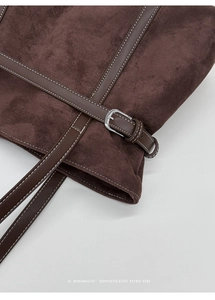 Close-up of brown suede tote bag featuring leather straps and silver buckle detail