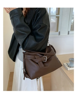 Detail of dark brown lychee leather tote bag with buckle design shown on model shoulder