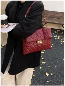 Detail of burgundy quilted leather shoulder bag with golden chain and twist-lock