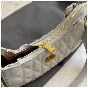 Close-up of golden zipper and quilted leather texture on a grey shoulder bag
