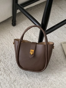 Vintage dark brown pebble leather bucket bag with gold lock on soft plush rug
